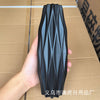 A black decorative plastic vase with a ribbed, Nordic style pattern is held against a brown cardboard box.