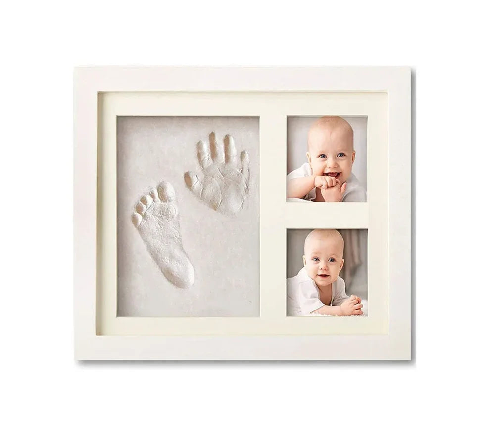 A white picture frame displaying three impressions: a baby's handprint, a footprint, and a portrait of a smiling baby.