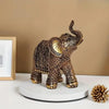 Vintage resin elephant ornament with gold detailing displayed on a white circular stand.