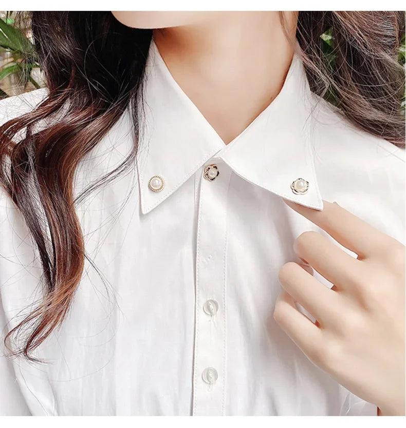 Close-up of a white collared shirt featuring pearl and rhinestone no-sew buttons.