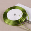 A spool of green satin ribbon for gift wrapping and DIY crafts resting on a white surface.