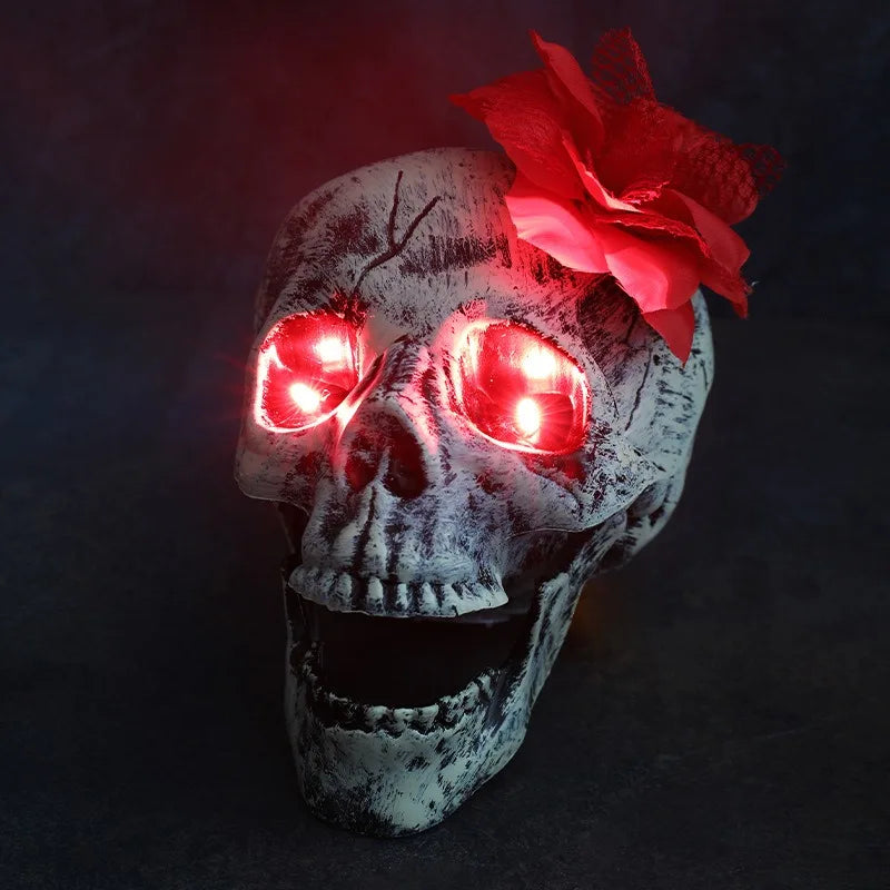 A skull with glowing red LED eyes and a red flower decoration for Halloween decor.
