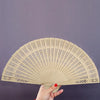 A set of twelve vintage wooden folding hand fans with intricate cutouts displayed against a gray background.