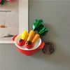 A set of playful food-shaped fridge magnets featuring a tomato, yellow pepper, and green leaf.