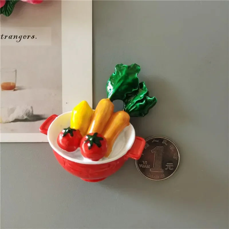 A set of playful food-shaped fridge magnets featuring a tomato, yellow pepper, and green leaf.