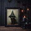 A dark framed canvas print featuring a black cat wearing a witch hat against a muted background.