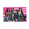 Un grupo de mujeres posando frente a un tapiz de arte con la bandera estadounidense rosa y blanca.