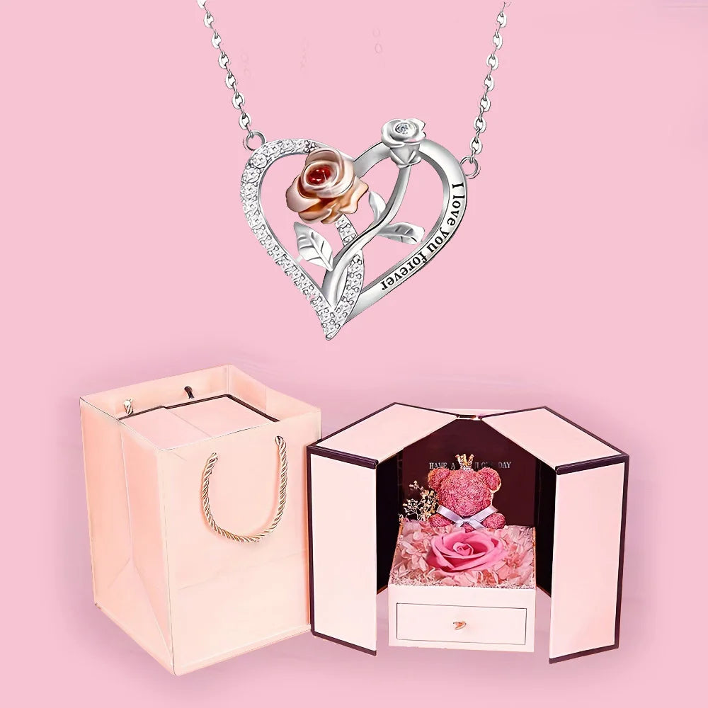 A silver heart pendant necklace featuring a rose and the inscription I love you forever displayed next to its pink gift box.