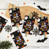 A collection of Halloween glow stick holder cards featuring bats, ghosts, and spiders arranged on a wooden board.
