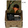 A hand-cranked wooden music box featuring a portrait of a woman in a dark hat, with internal mechanisms visible.