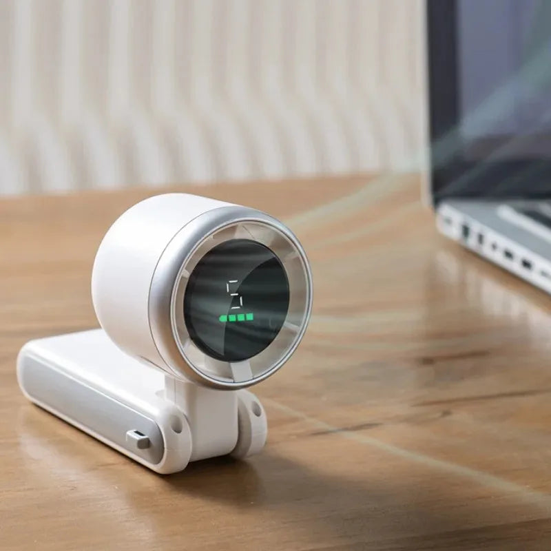 A white foldable mini handheld fan with a digital display rests on a wooden surface.