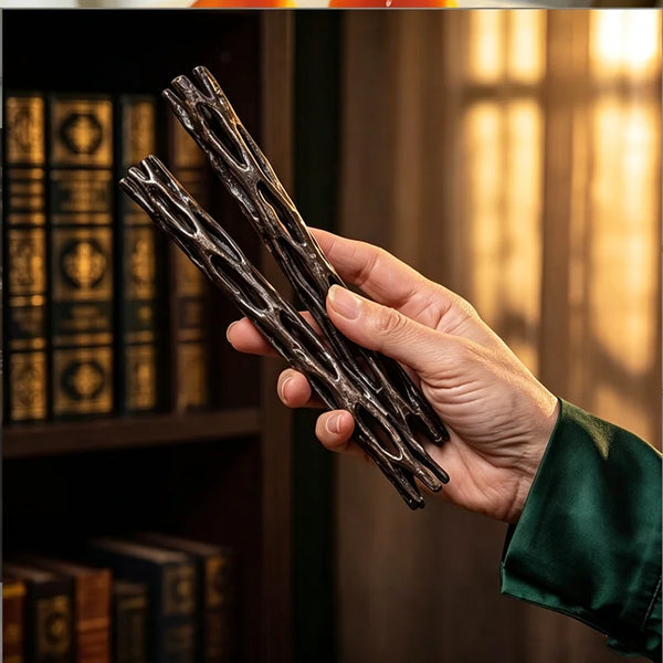 A hand holds two dark, twisted willow sticks used as a good luck gift or breakable wish box.