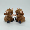 A small, brown Highland cow statue with horns and large eyes, displayed against a white background.