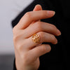 A close-up of a hand wearing a gold signet ring with the Leviathan cross design.