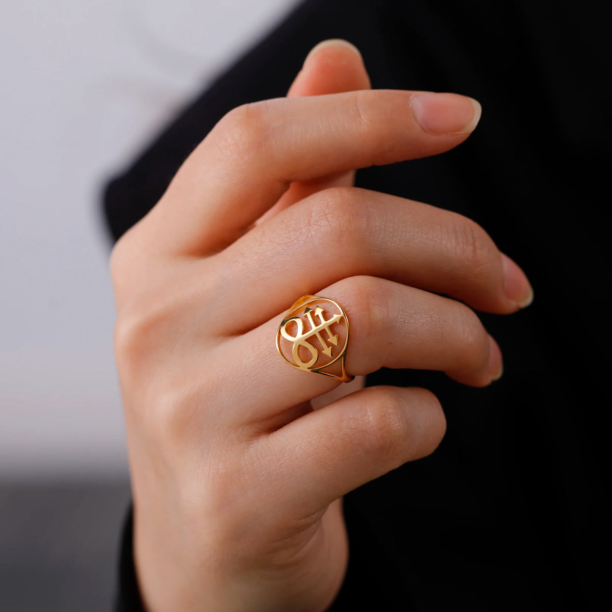 A close-up of a hand wearing a gold signet ring with the Leviathan cross design.