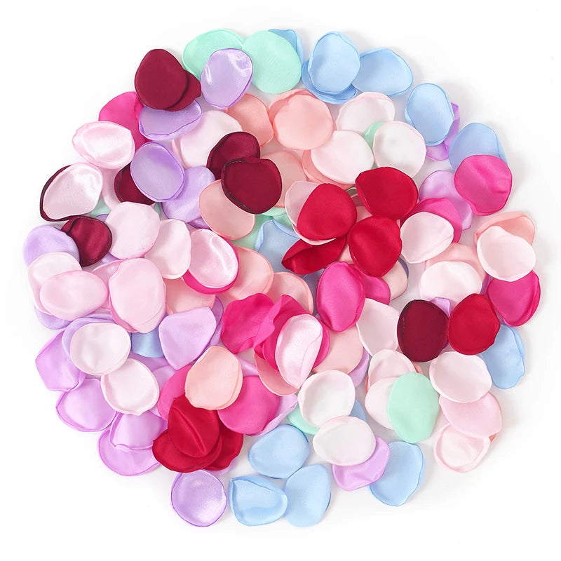 Una colorido arreglo de pétalos de flores de seda artificiales en tonos rosa, morado y azul.