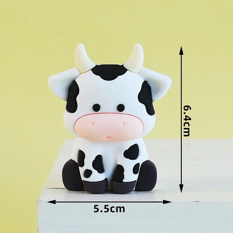 A white and black cow-shaped cake topper with horns, standing on a wooden surface.