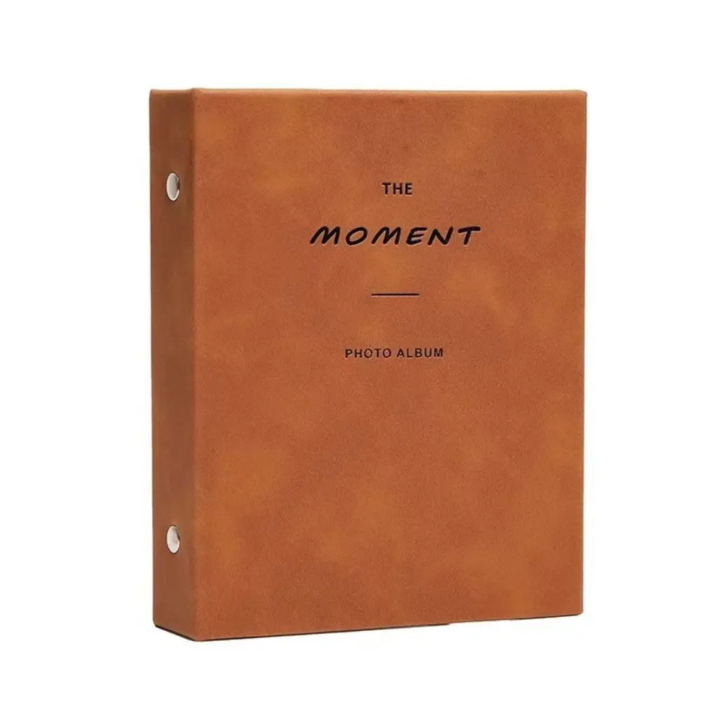 A brown leather-bound photo album titled The Moment Photo Album with a simple line separator.