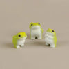 A set of six cute mini resin frog figurines in yellow and white sitting on a neutral background.