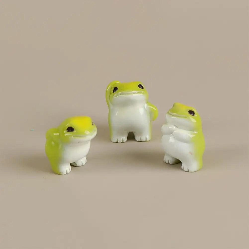 A set of six cute mini resin frog figurines in yellow and white sitting on a neutral background.
