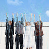Four people are throwing blue confetti streamers into the air against a light blue sky.