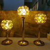 Three golden crystal candle holders with spherical glass bulbs displayed on a light surface.
