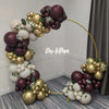 A balloon garland arch featuring burgundy, gold, and white balloons displayed against a gray background.