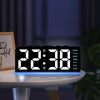 Reloj de alarma LED digital mostrando las 22:38 con día de la semana y luz nocturna sobre una mesa blanca.