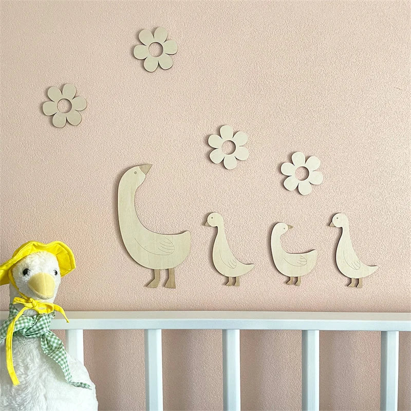 Handcrafted wooden goose wall art with floral accents displayed on a pink wall above a white railing.