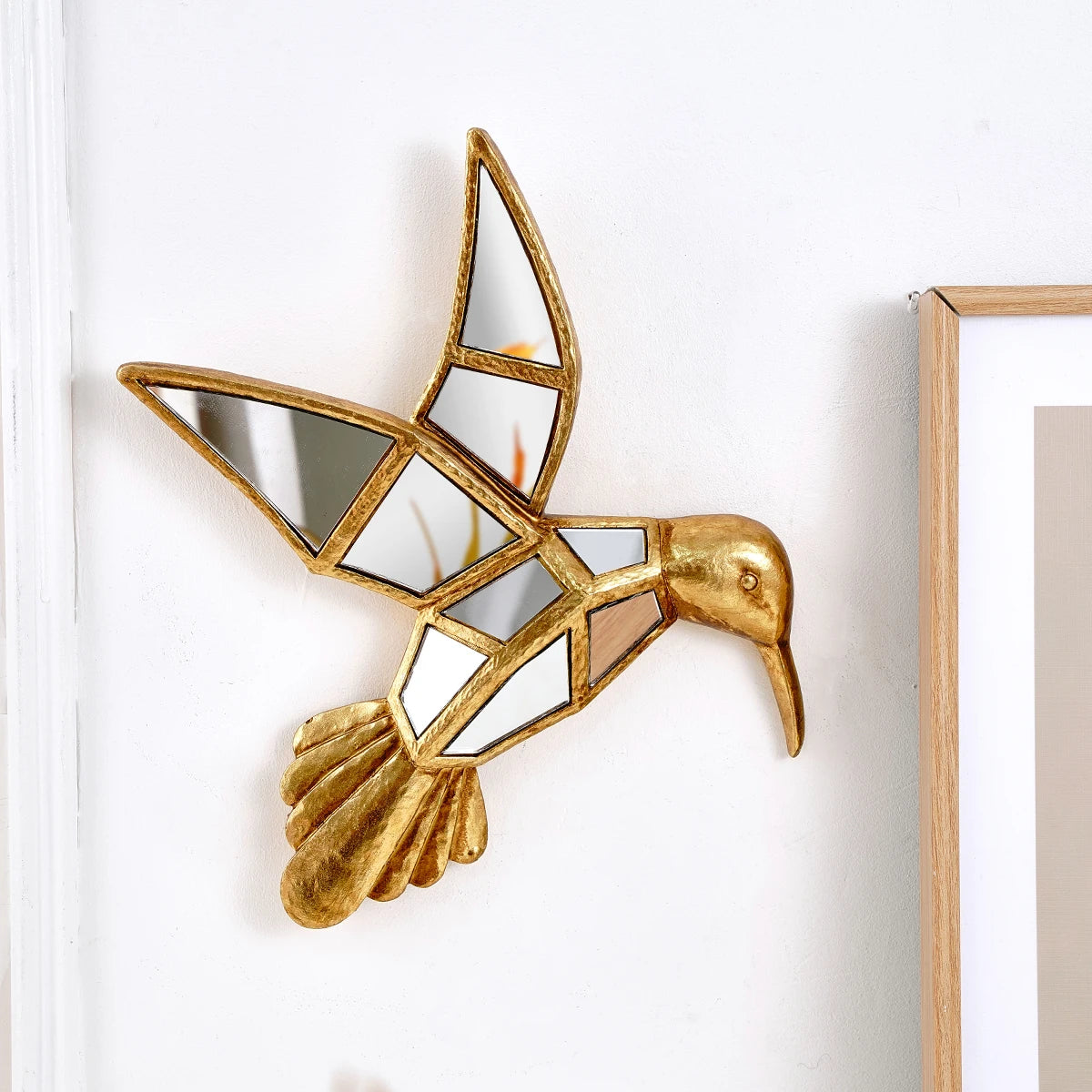 A gold resin animal wall hanging decor shaped like a bird, mounted on a white wall.