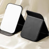 A black foldable vanity mirror with an adjustable stand is shown against a light fabric background.