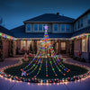 A large Christmas tree made of solar-powered lights stands in a garden setting at dusk.
