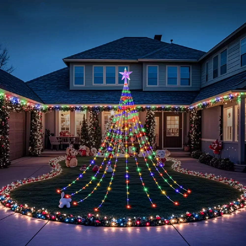 A large Christmas tree made of solar-powered lights stands in a garden setting at dusk.