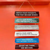 A vertical wooden sign with layered text instructing to watch thoughts, words, actions, habits, and character for destiny.