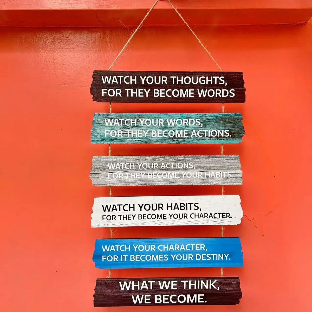 A vertical wooden sign with layered text instructing to watch thoughts, words, actions, habits, and character for destiny.