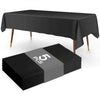 A black disposable plastic tablecloth is draped over a rectangular table, shown next to a stack of five black tablecloths.