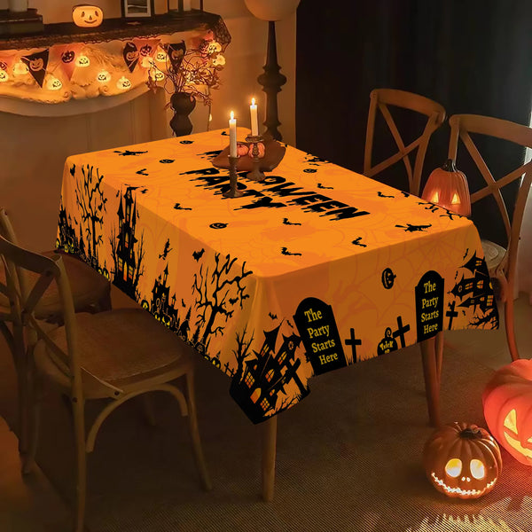 An orange tablecloth with a black silhouette pattern of trees and spooky elements is displayed on a table.