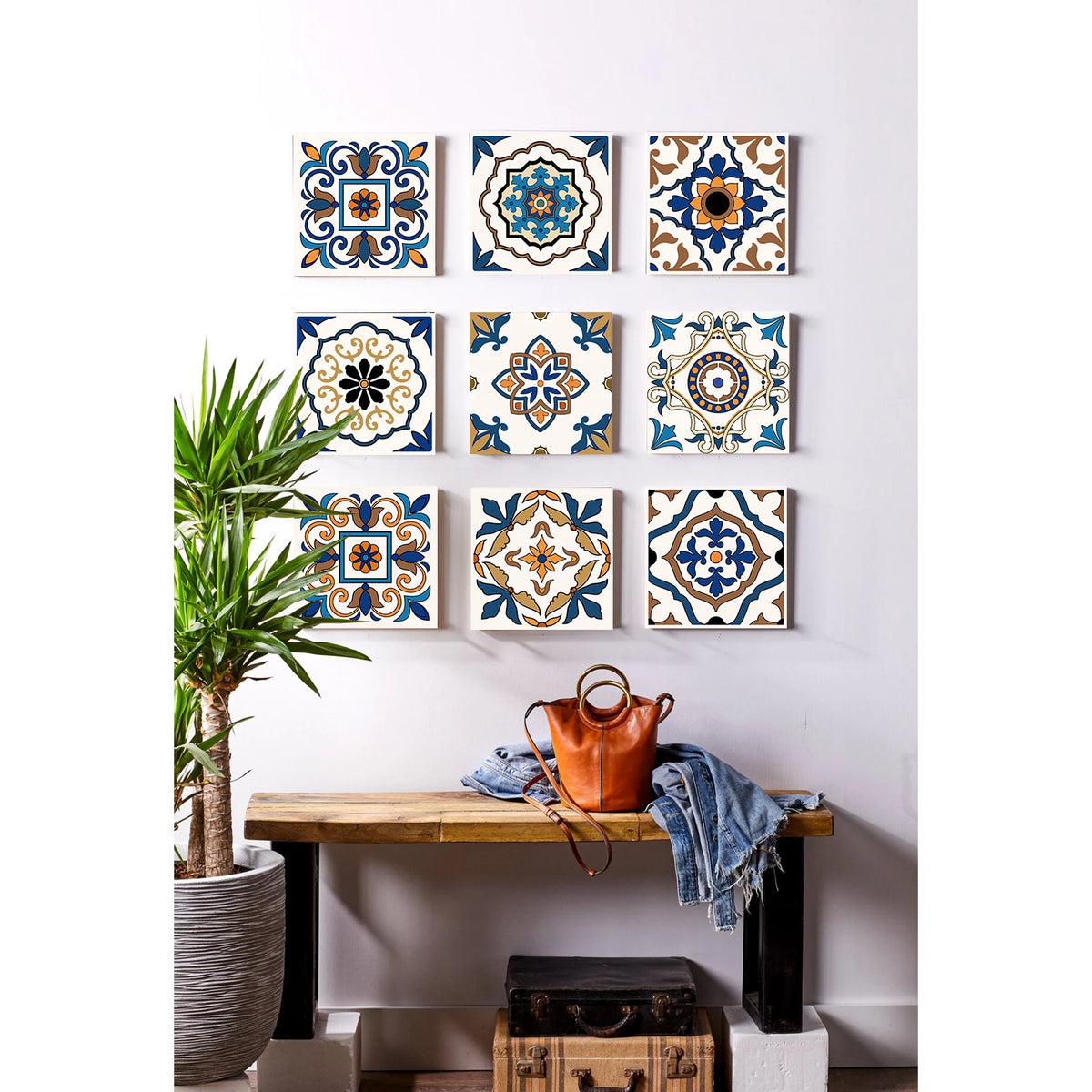 A display of various patterned self-adhesive tile wall stickers on a white wall, next to a wooden shelf.