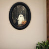 Vintage wall art featuring a ghost witch and a black cat in an oval frame.