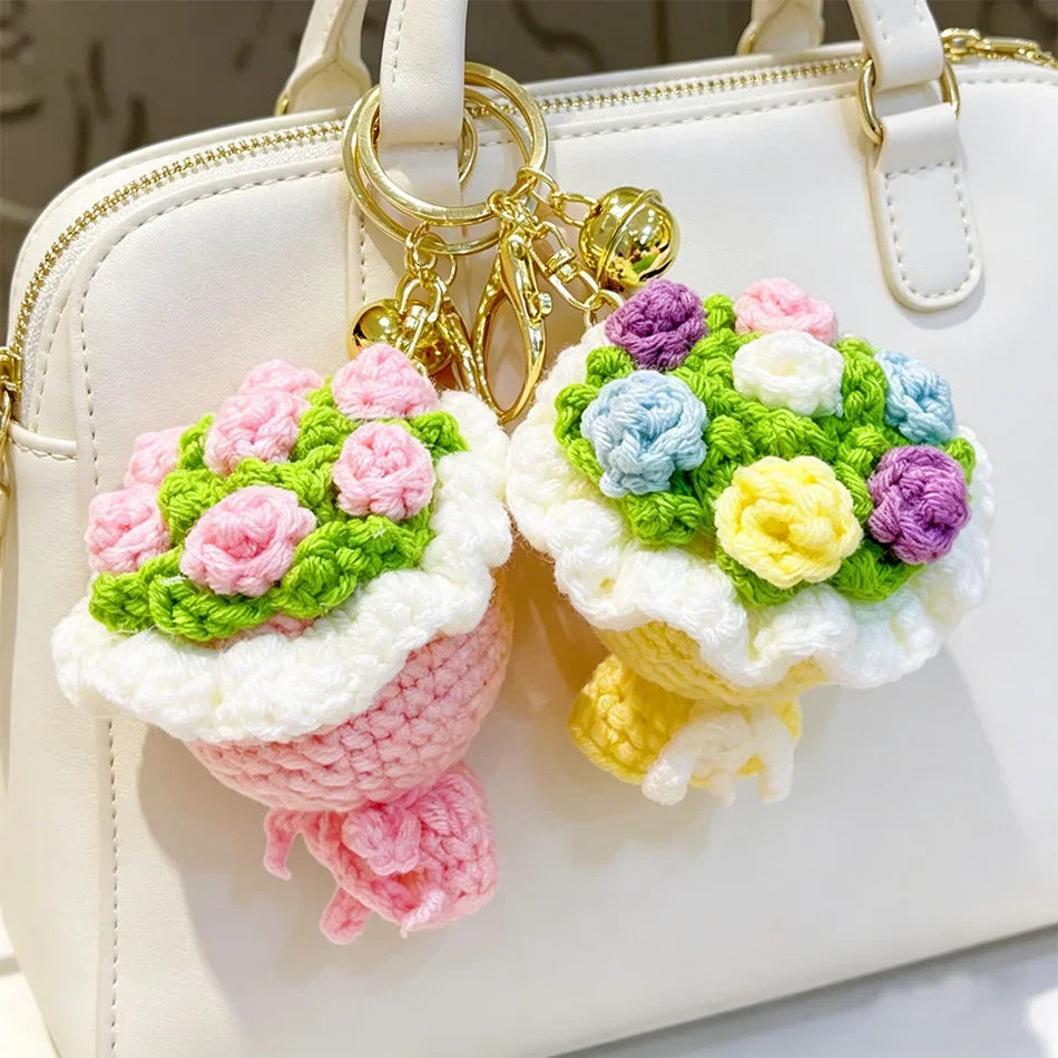 A white handbag with a gold chain keychain featuring colorful handmade crochet flowers.