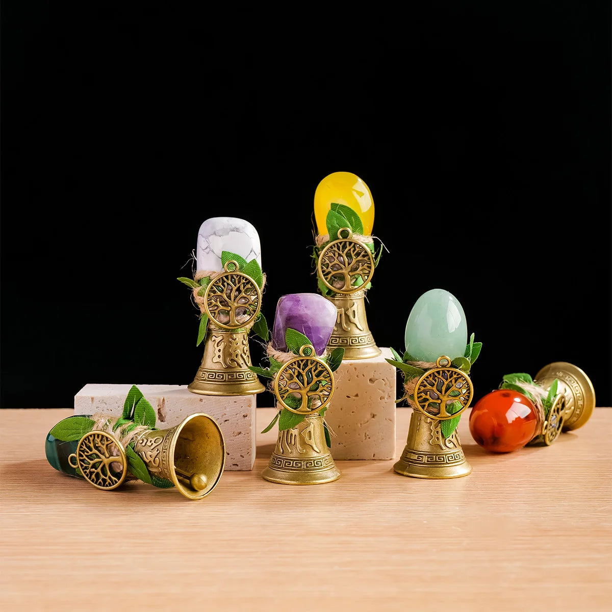 A collection of natural crystal tree of life chimes in various colors, including yellow, purple, and green, displayed on a wo