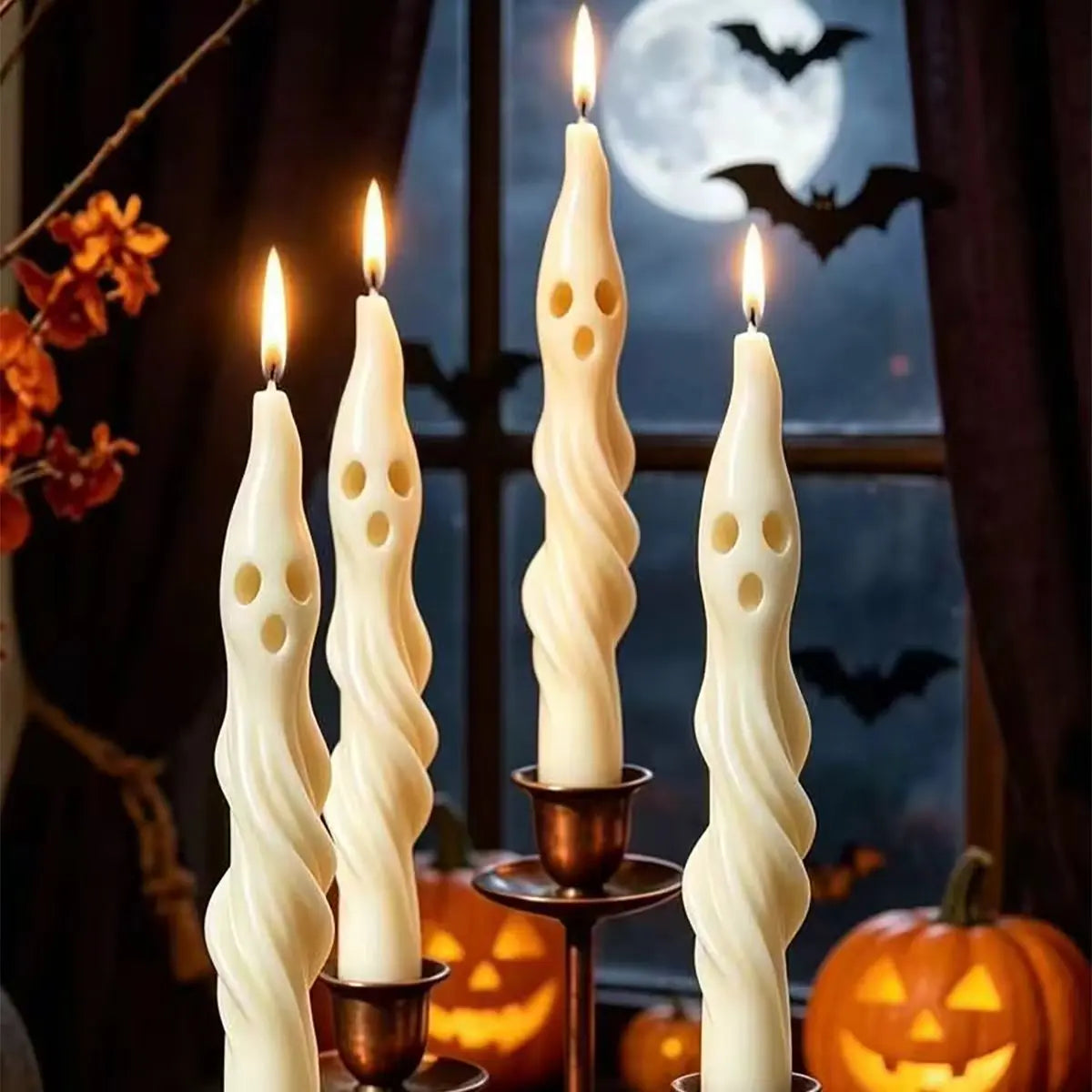 A set of white soy candles shaped like ghosts and mummies displayed in a dark, autumnal Halloween setting.