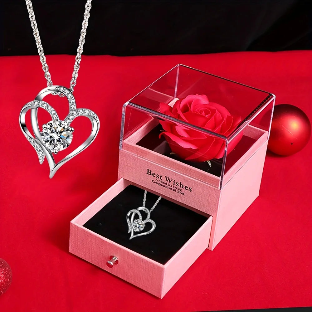 A pink box containing a red rose and a silver heart-shaped necklace gift set