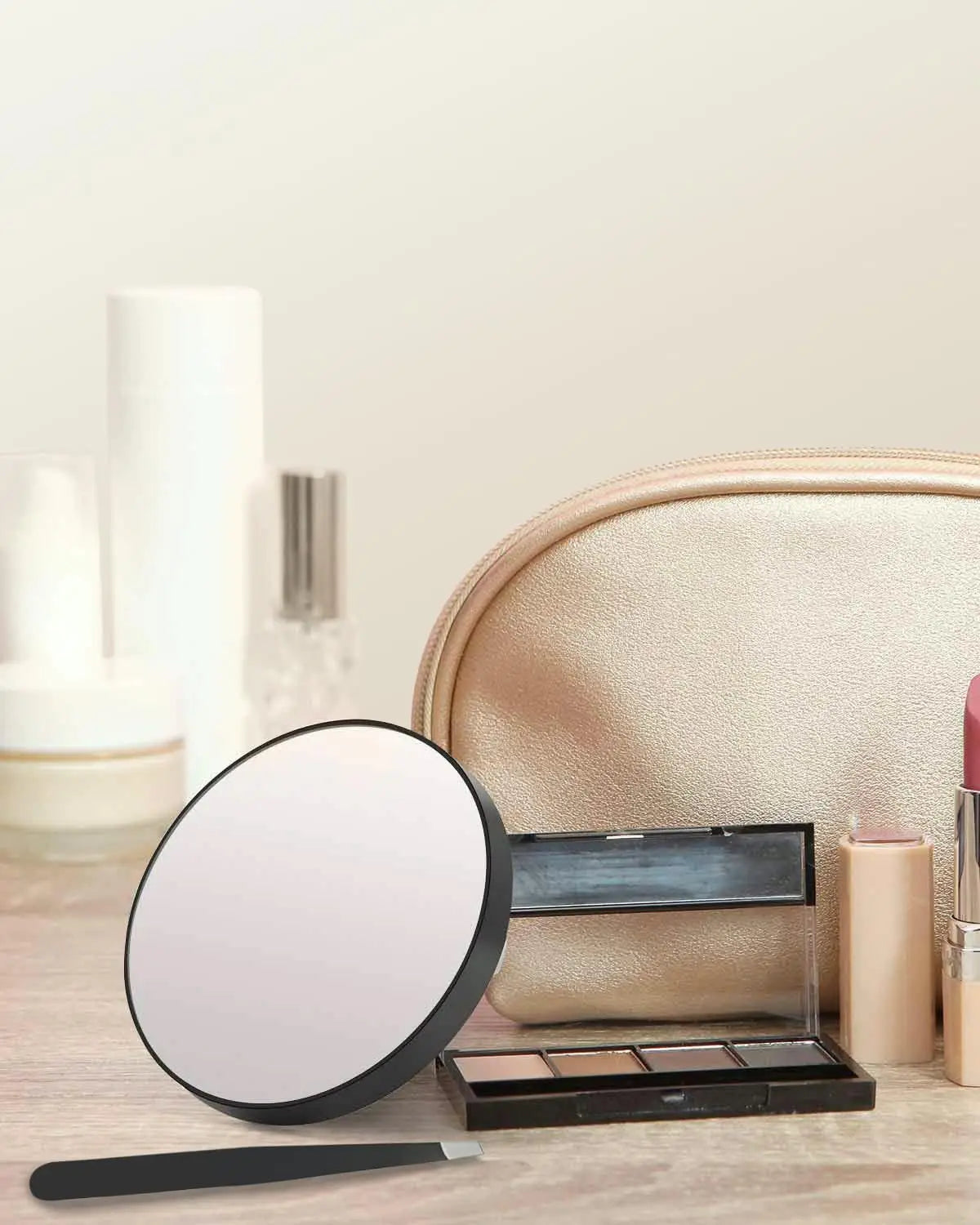 A round magnifying compact mirror with a suction cup and a rectangular makeup palette are shown on a wooden surface.