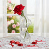 A red rose is placed in an artistic glass human body vase on a lace tablecloth.
