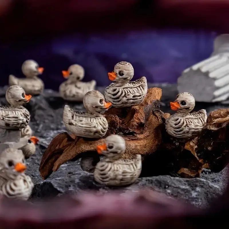 A collection of small resin duck figurines with orange beaks perched on dark, textured material.