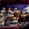 A collection of small, gray resin duck figurines with orange beaks perched on dark, textured material.