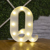 A white alphabet letter Q made of LED lights resting on a wooden surface.