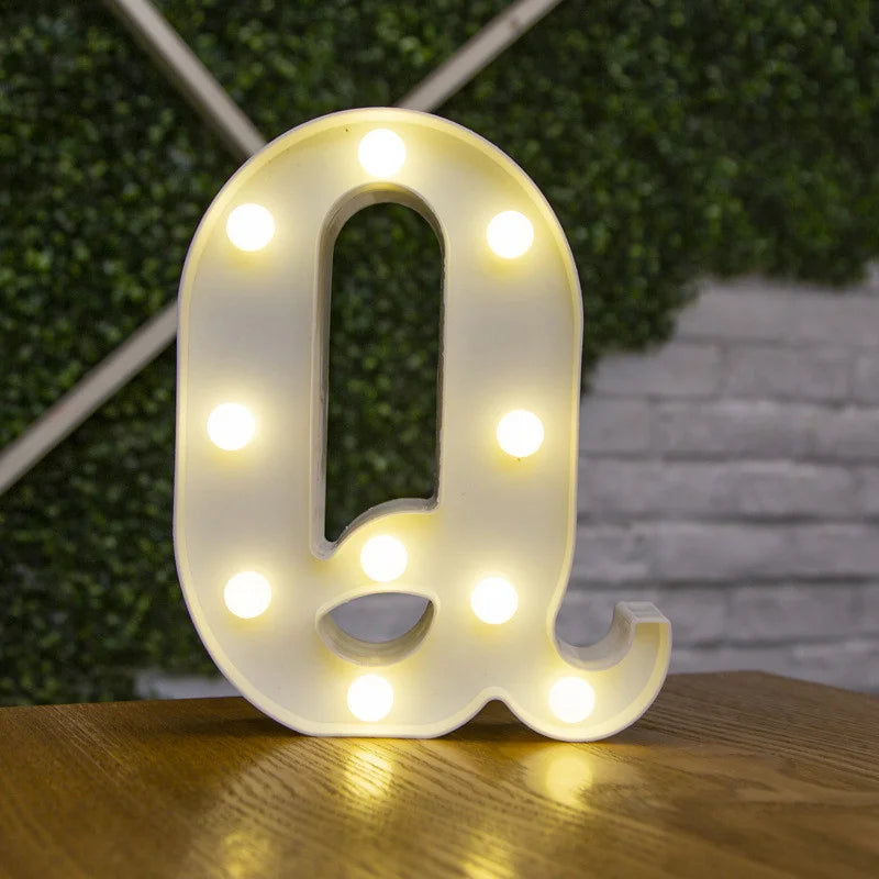 A white alphabet letter Q made of LED lights resting on a wooden surface.