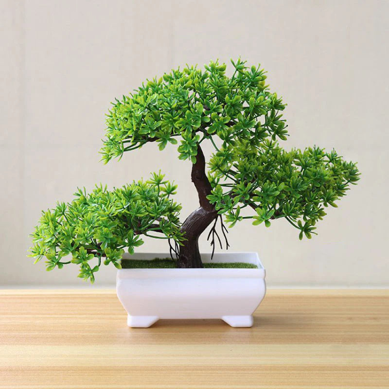 A small artificial tree bonsai decoration with vibrant green foliage planted in a white rectangular pot.